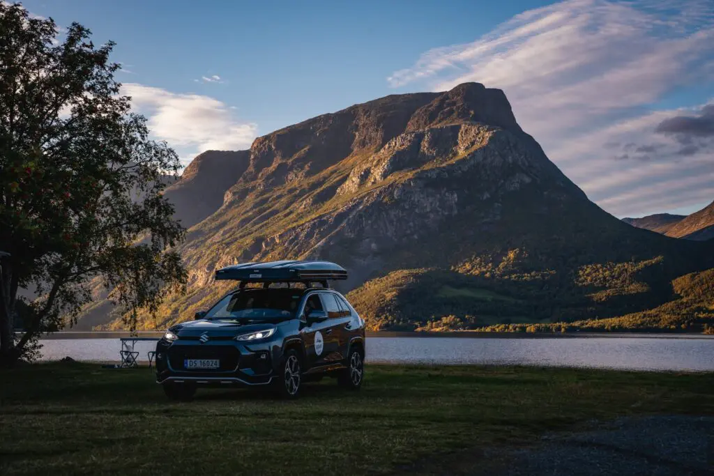 car with rooftop tent parked by a lake in Norway mountains