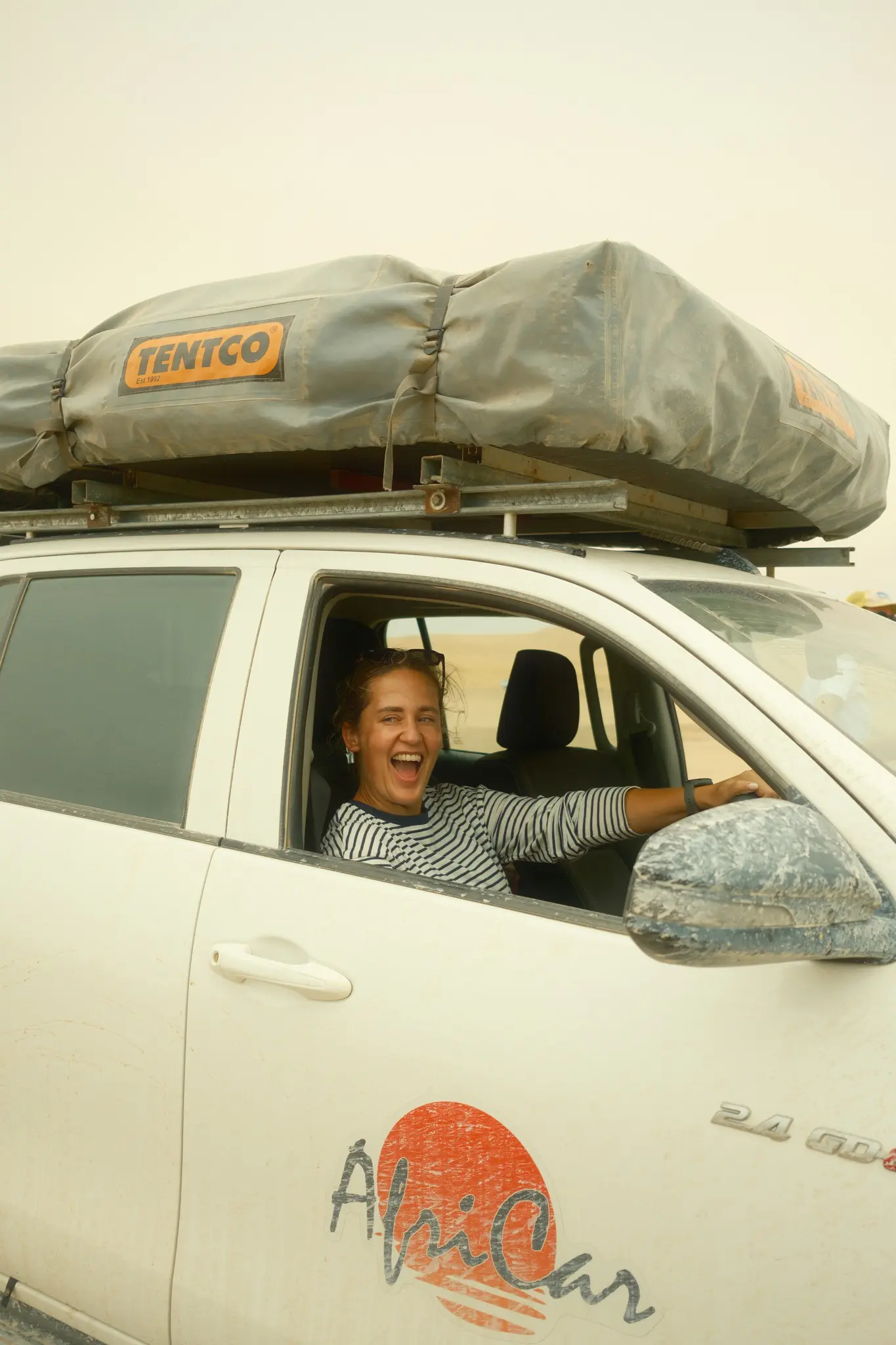 woman laughing in a 4x4 with a rooftop tent in Namibia