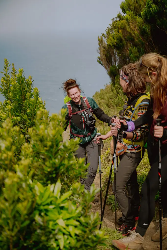 three women hiking on a mountain trail overlooking the sea